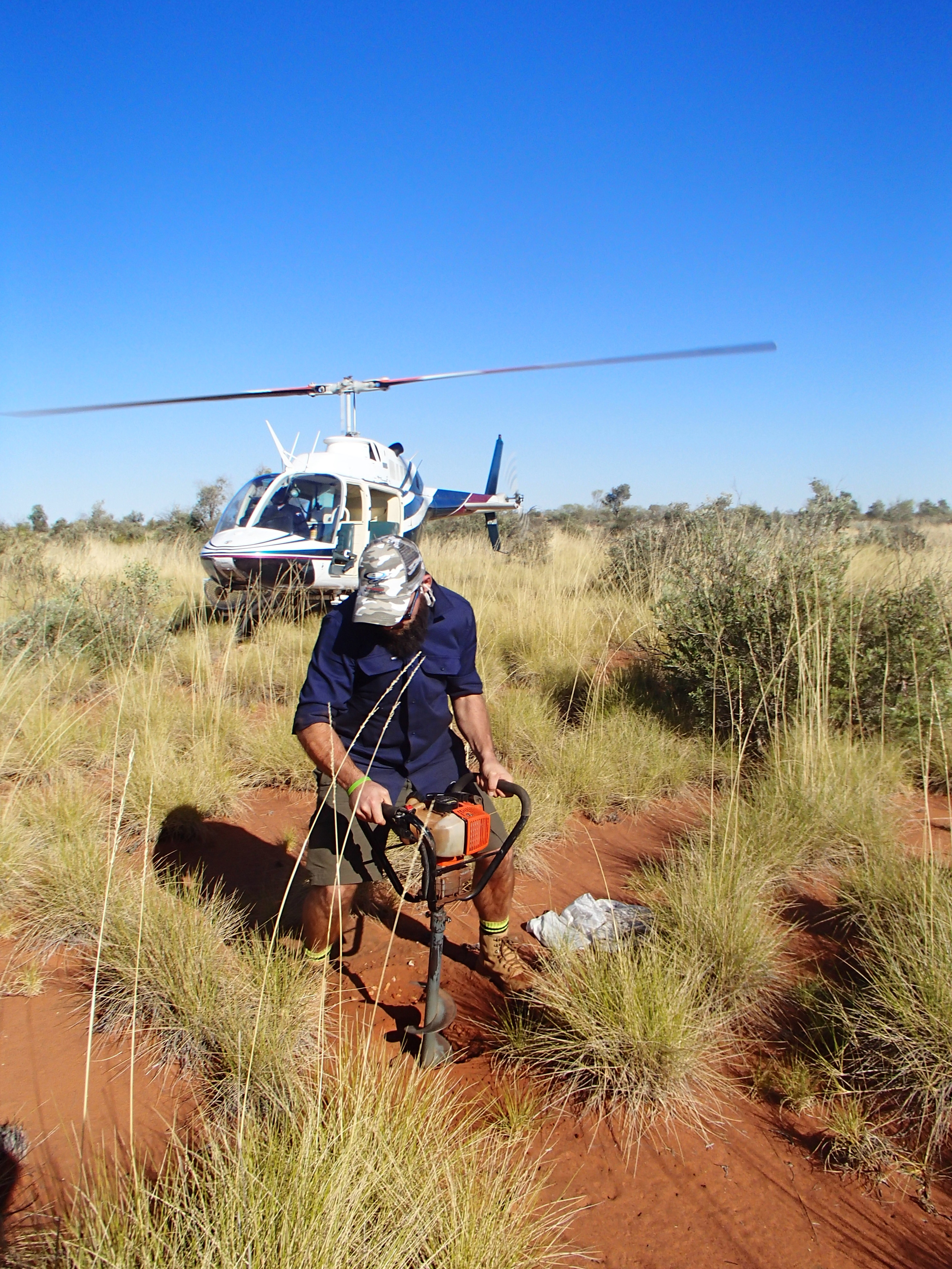 In areas of weakly consolidated regolith, a power auger is used to collect regolith samples. The auger, with a 10 cm diameter bit, has a maximum penetration depth of 90 cm, and can fit in the skid-mounted basket on the helicopter. Sample collection and recording of site information can be carried out in approximately seven minutes, avoiding a shut-down of the helicopter. - Paul Morris, Gov of WA